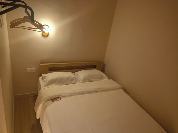 A small, single-bed room with a wooden headboard, white bedding, and a wall-mounted light fixture. - Keteri Boutique Hotel (Kangar)