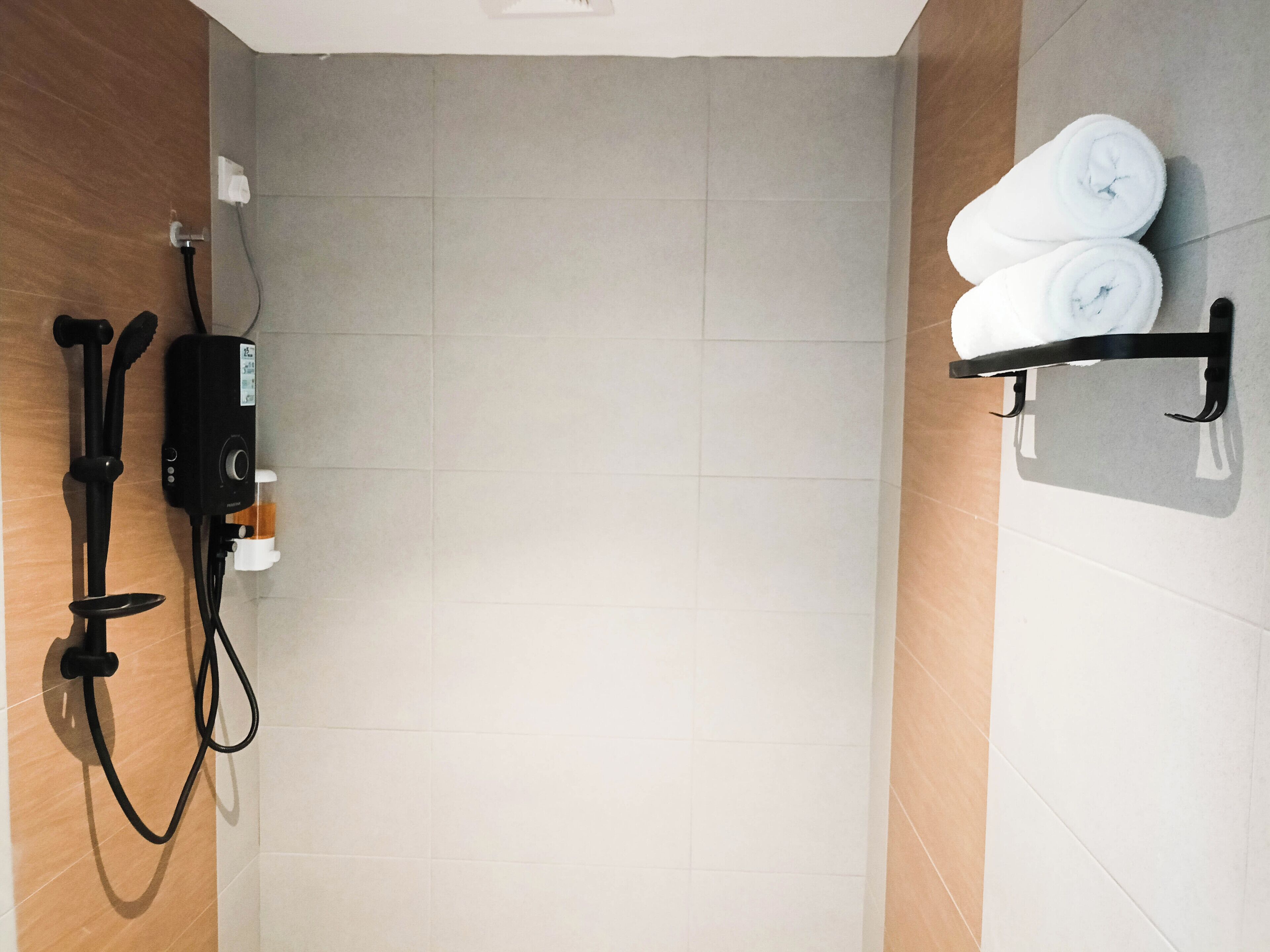 Un bagno con doccia, un portasciugamani con asciugamani e uno scaldabagno.