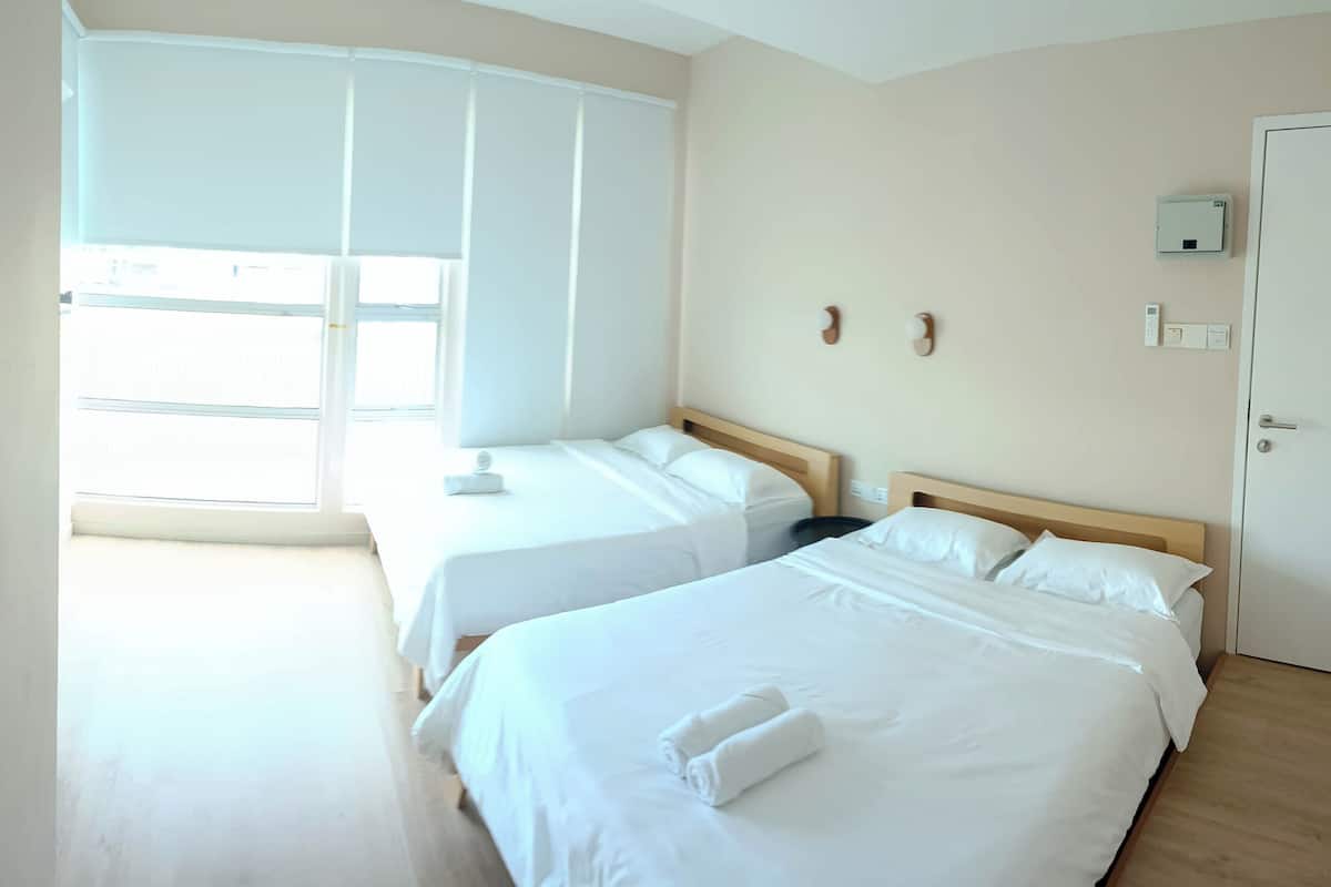 Ein Hotelzimmer mit zwei Betten, einem großen Fenster, einem Thermostat und einer Tür.