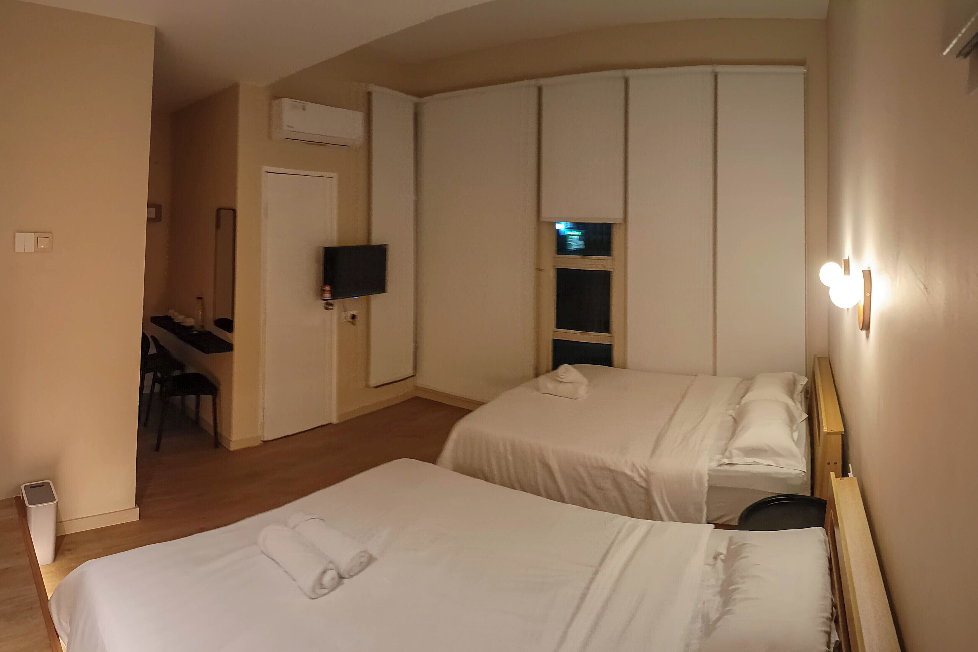 Ett hotellrum med två sängar, ett skrivbord, en stol och en tv.