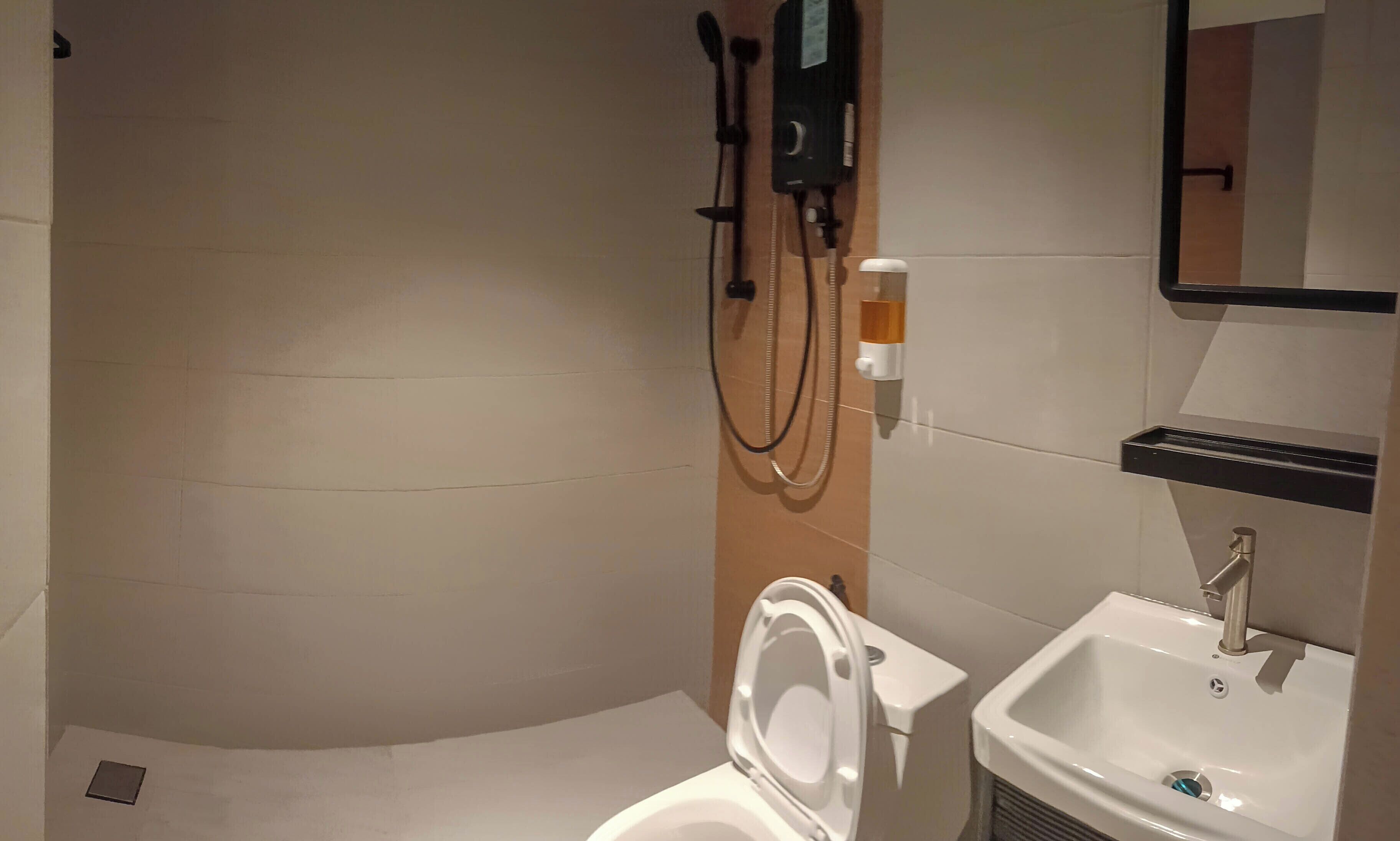 A bathroom with a toilet, sink, and shower area.