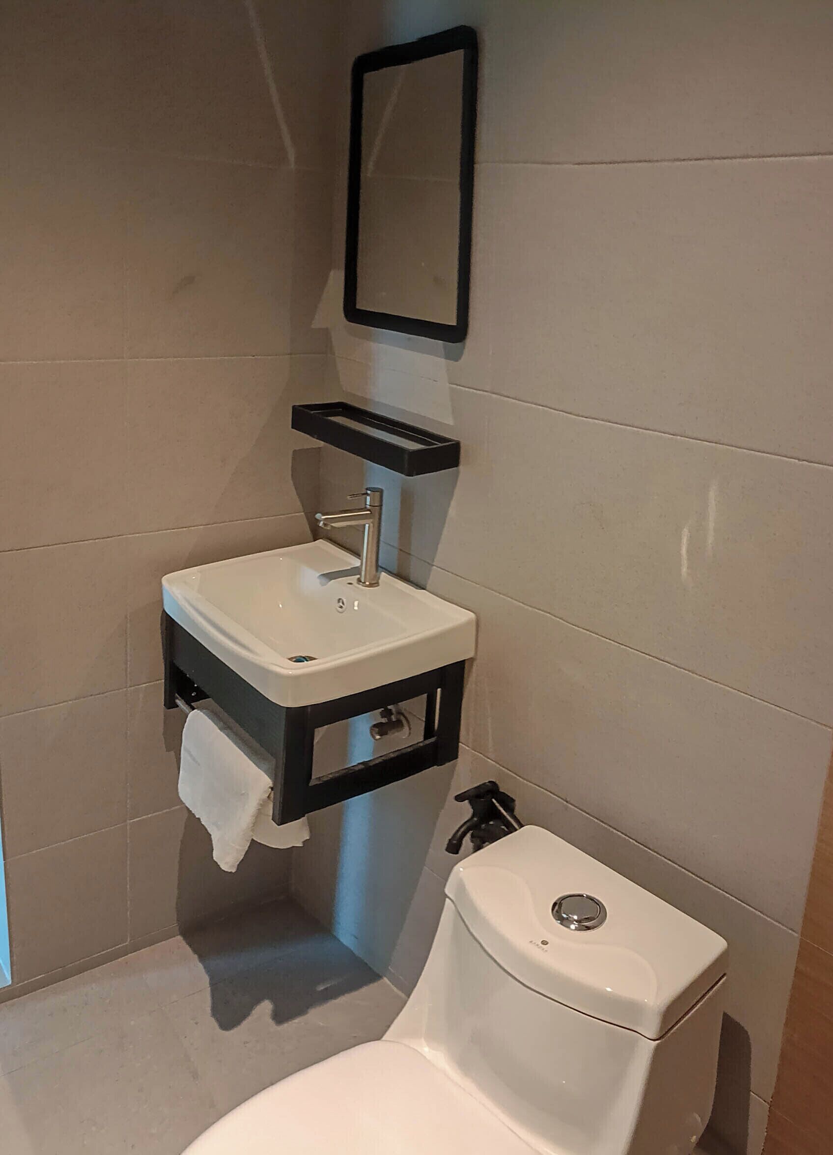A bathroom with a white sink, a mirror, and a toilet.