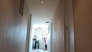 A long, narrow hallway with a wooden floor, white walls, and a ceiling with recessed lighting. There is a door on the right and a window on the left. - Keteri Boutique Hotel (Kangar)