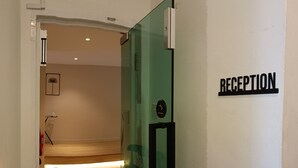 A reception area with a glass door, a reception desk, and a wall-mounted sign that reads "RECEPTION". - Keteri Boutique Hotel (Kangar)