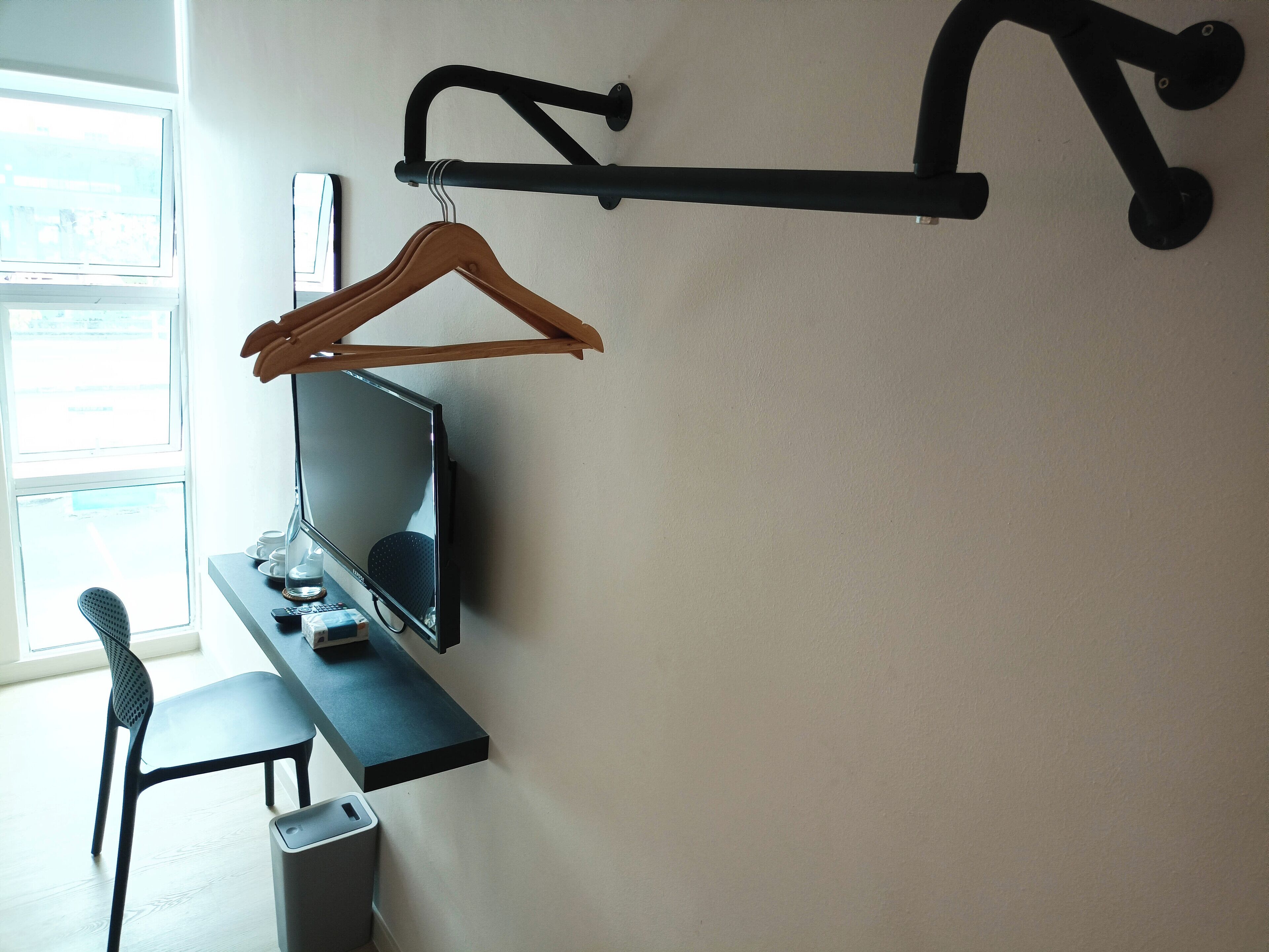 A modern office space with a desk, chair, and a wall-mounted rack with a hanger.