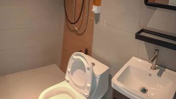 Un baño moderno con inodoro, lavamanos y ducha.