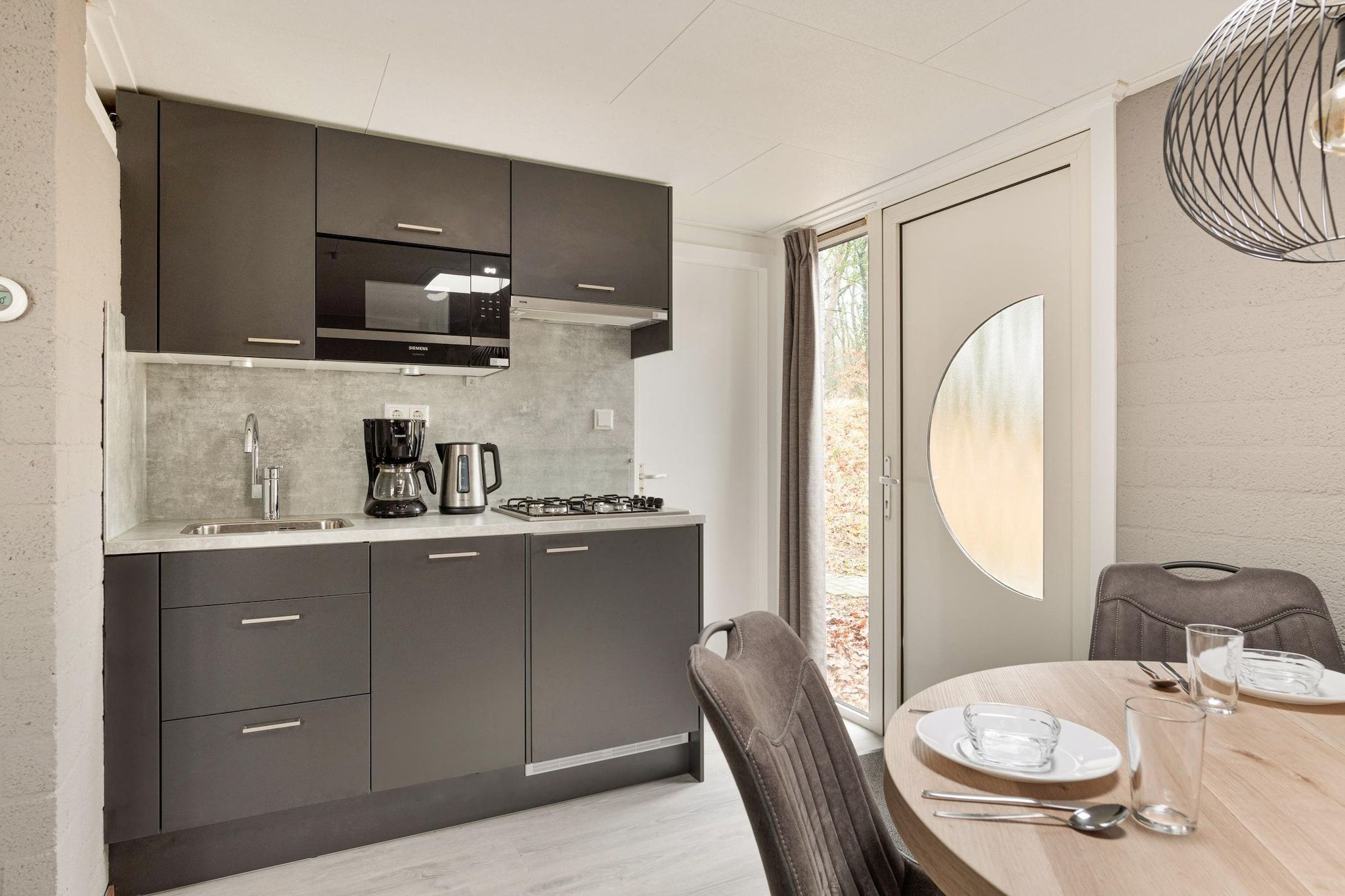 Een moderne keuken met donkere kastjes, een Siemens magnetron en een gasfornuis.