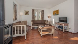 Una sala de estar con sofá, mesa de centro, televisor, chimenea y ventana con cortinas.