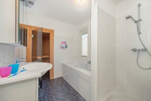 Une salle de bain moderne avec un lavabo blanc, une douche en verre et une baignoire.