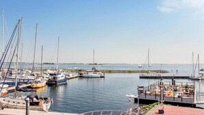 Un puerto deportivo con varias embarcaciones amarradas, un muelle con asientos y aguas tranquilas.