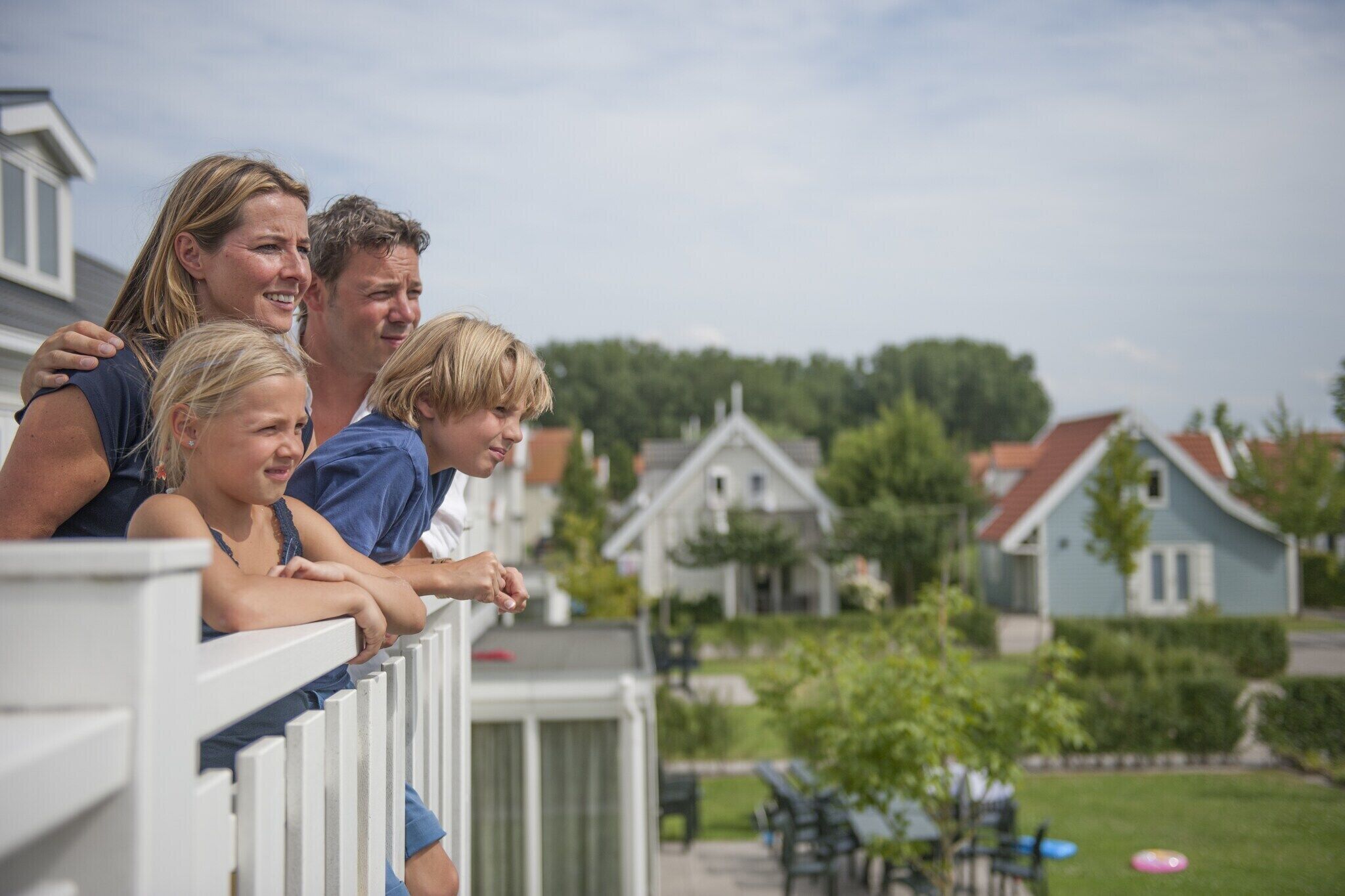 Una familia en un balcón con vista a un barrio residencial.