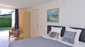 Ein Schlafzimmer mit Bett, Stuhl, Kleiderschrank und einem Bild an der Wand.