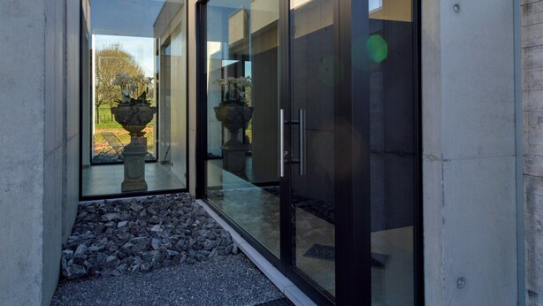 A modern building with large glass doors and windows, a stone pathway, and outdoor sculptures. - Dalhem Villa with Garden (Dalhem)
