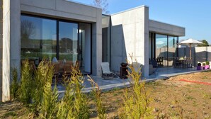 A modern building with large glass windows, outdoor seating, and a patio area. - Dalhem Villa with Garden (Dalhem)