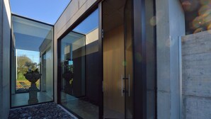 A modern building with large glass doors and a stone pathway leading to a garden. - Dalhem Villa with Garden (Dalhem)
