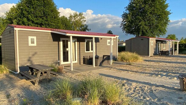 A row of small, single-story cabins with a red roof, each featuring a door and a window. - Chalet near Loonse and Drunense Duinen (Udenhout)