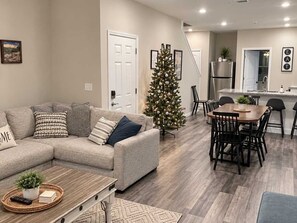 A living room with a sofa, coffee table, and a Christmas tree. There is a dining area with a table and chairs. - 3111 Close to Silver Dollar City, Save 10% on tix (Branson)