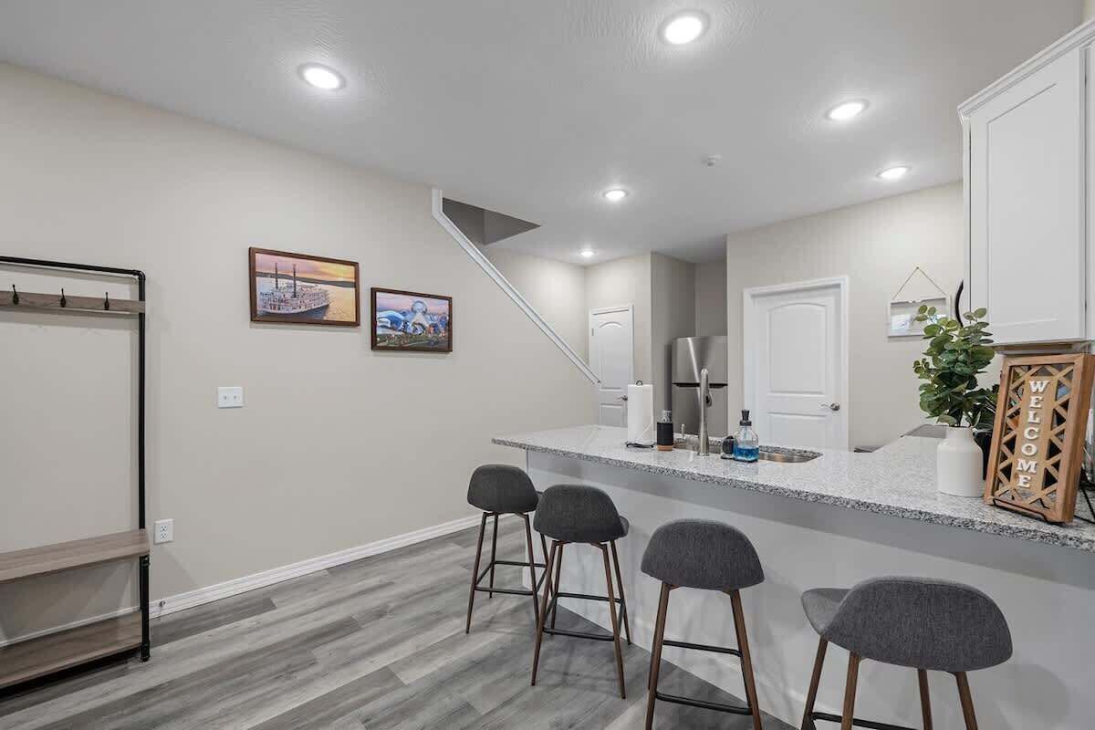 Una cuina moderna amb zona de bar, una escala i una porta que dona a una altra habitació.
