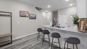 A modern kitchen with a bar area, a staircase, and a door leading to another room. - 3111 Close to Silver Dollar City, Save 10% on tix (Branson)