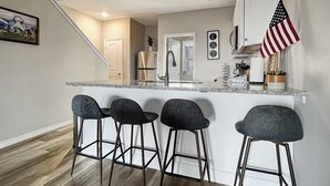 A kitchen with a central island, bar stools, a refrigerator, and an American flag. - 3111 Close to Silver Dollar City, Save 10% on tix (Branson)