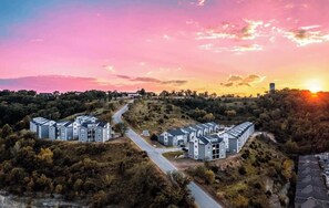 Un quartier résidentiel avec des immeubles modernes, une route sinueuse et un coucher de soleil en arrière-plan.