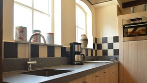 Une cuisine équipée d’un évier à deux bacs, d’une machine à café et d’un crédence à carreaux.