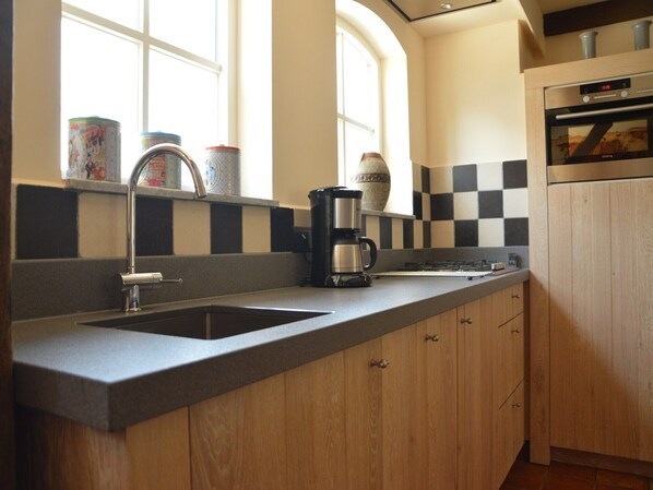A kitchen with a double sink, a coffee maker, and a checkered backsplash. - Family Home w/ Trampoline (Haaren)