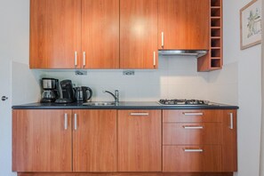 A kitchen with wooden cabinets, a gas stove, a coffee maker, and a sink. - Charming Villa in Natural Surroundings (Arcen)