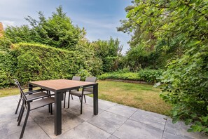 An outdoor patio with a table and chairs, surrounded by lush greenery. - Charming Villa in Natural Surroundings (Arcen)