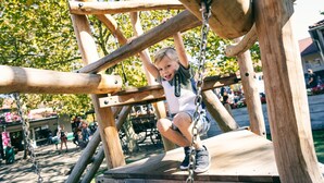 A child climbing a wooden play structure at a park.
