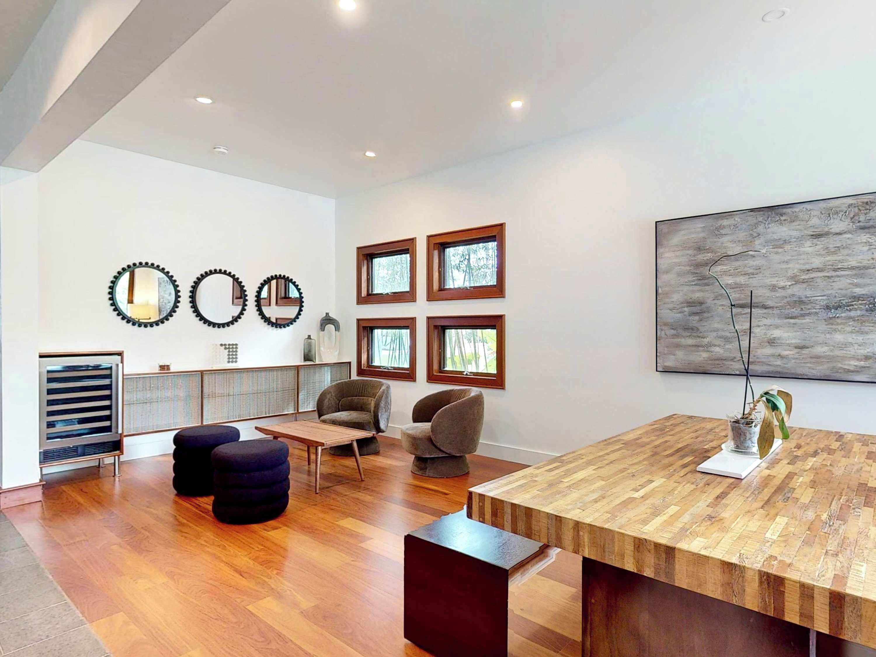 A modern living room with a wooden dining table, comfortable seating, and a large abstract painting on the wall.