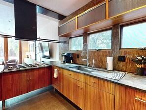 Une cuisine moderne avec des meubles en bois, une cuisinière encastrée et une grande fenêtre.