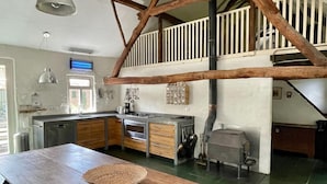 A spacious kitchen with wooden beams, a dining table, and a large window. - Farmhouse in Stramproy near Forest (Stramproy)