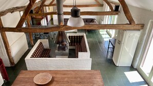 A rustic interior with exposed wooden beams, a central table with a woven basket, and a patterned sofa. - Farmhouse in Stramproy near Forest (Stramproy)