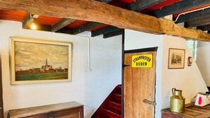 A room with a wooden bench, a staircase, a door labeled "Stramproyer Bieren," and a painting on the wall. - Farmhouse in Stramproy near Forest (Stramproy)