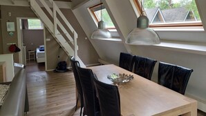 A dining area with a wooden table and black chairs, a staircase, and large windows with a view of the outside. - Chalet in Tyrol near Ski Slope (Stramproy)