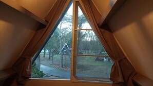 A room with a triangular window and a view of a forested area outside. - Chalet in Tyrol near Ski Slope (Stramproy)