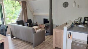 A modern living room with a sofa, a TV, and a fireplace. There is a kitchen area with a sink and a coffee maker. - Chalet in Tyrol near Ski Slope (Stramproy)