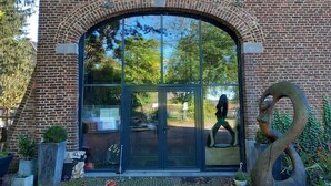 Ein Backsteinhaus mit großem Bogenportal, Glastür und einer Metallskulptur eines Schwans.