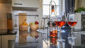 Eine Küchenarbeitsplatte mit einer Flasche Rotwein, zwei Weingläsern und einer Obstschale.