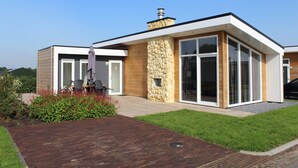 A modern two-story house with a stone facade, large glass windows, and a brick pathway leading to the entrance. - Charming Retreat for Your Escape (Bemelen)