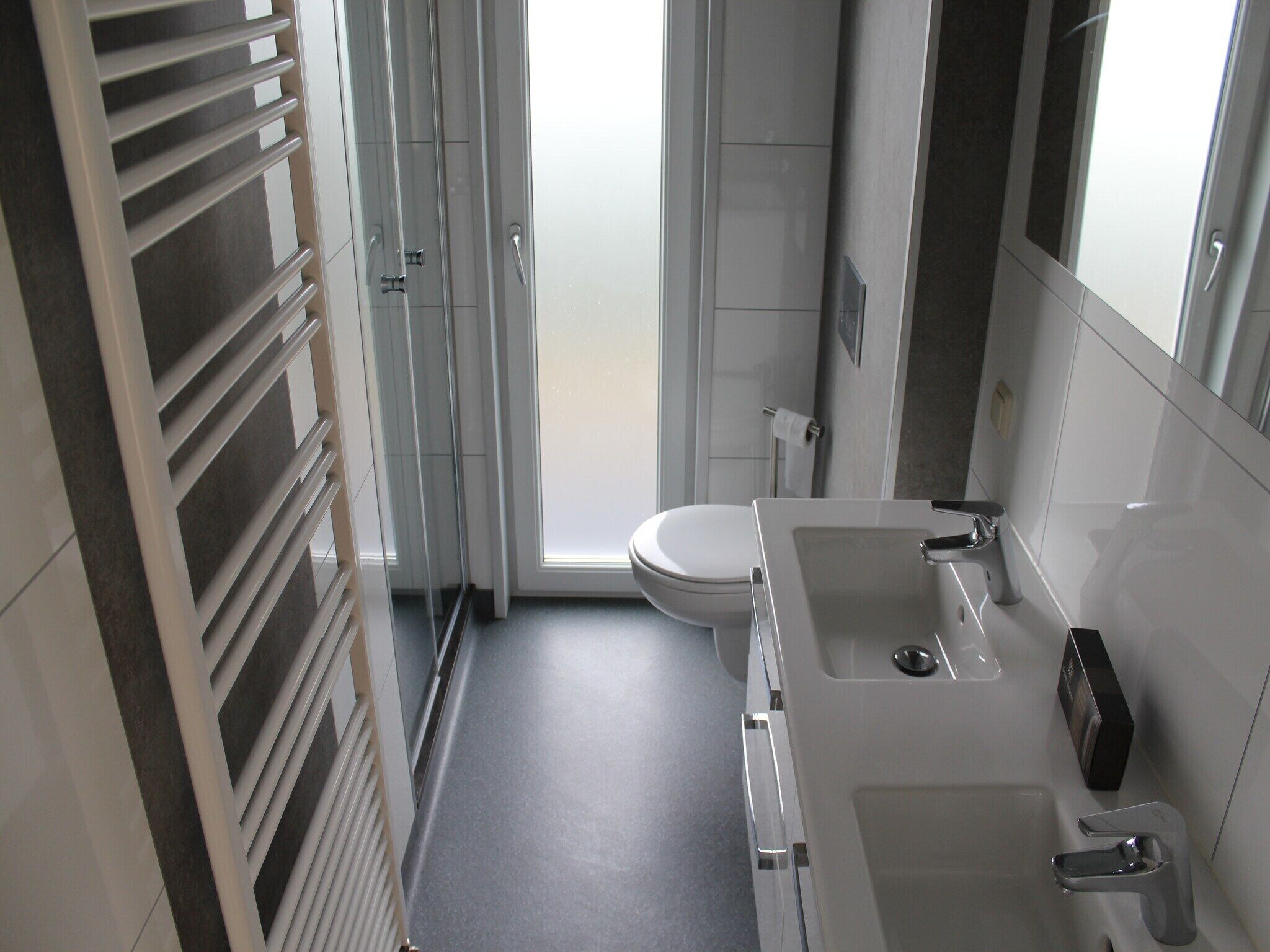 Un baño moderno con inodoro, lavamanos y ducha.