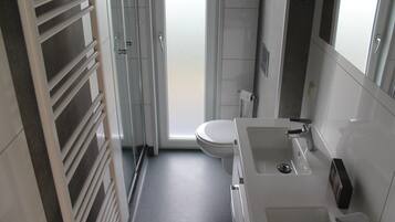 Un baño moderno con inodoro, lavamanos y ducha.