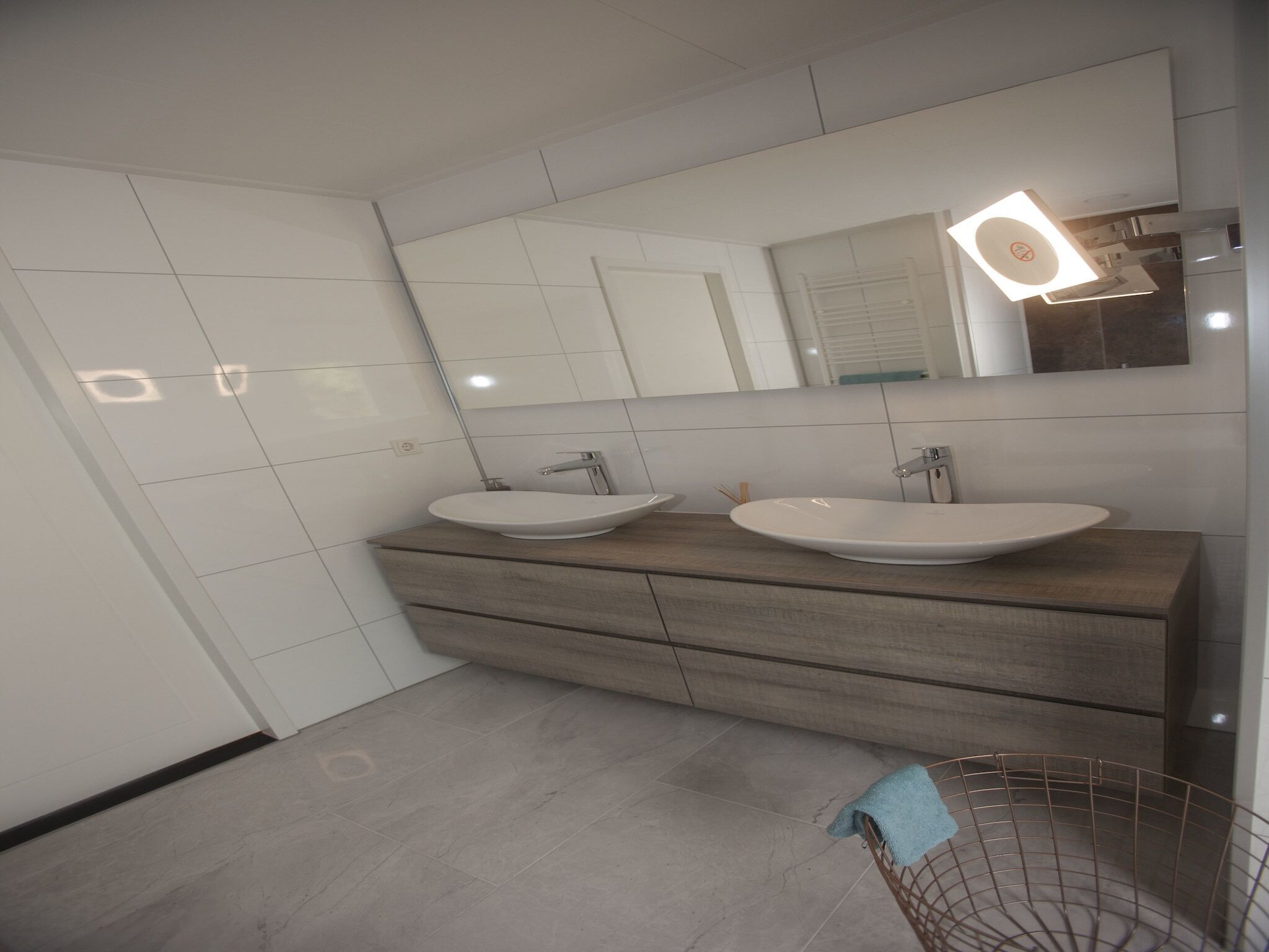 A modern bathroom with two sinks, a large mirror, and a towel rack.