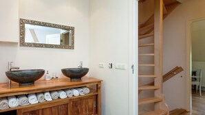 A bathroom with two vessel sinks, a wooden vanity with towels, a mirror, and a wooden staircase. - Scenic Gulp Valley Stay (Slenaken)
