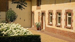 A brick building with a large beige door, a potted plant, and white flowers in the foreground. - Farmhouse Wijlre near Scenic Lake (Wijlre)