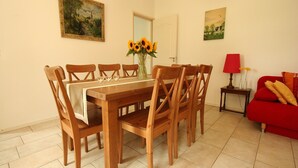 A dining area with a wooden table and chairs, a vase with sunflowers, and a red sofa. - Wijlre Farmhouse stay (Wijlre)