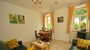 A living room with a green sofa, a wooden coffee table, and a dining area with a table and chairs. - Wijlre Farmhouse stay (Wijlre)