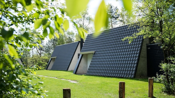 Un bâtiment moderne doté d’un toit en pente, entouré d’une pelouse bien entretenue et de poteaux en bois.
