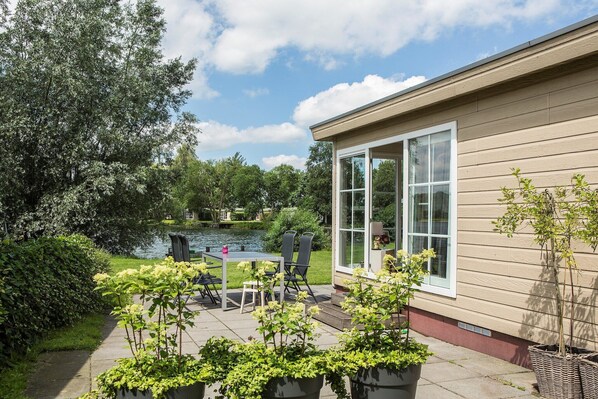 A patio with a table and chairs, a small pond, and a house with a sliding glass door.